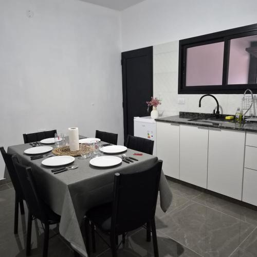 a dining room table with black chairs and a kitchen at Departamento LUNA DE BELEN in Belén