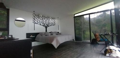 a bedroom with a bed and a tree on the wall at Cabaña Guane in Pacho