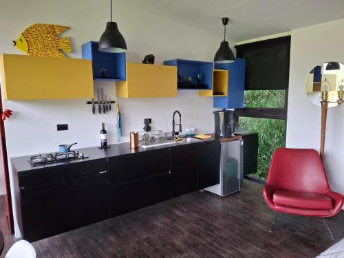 a kitchen with blue and yellow cabinets and a red chair at Cabaña Guane in Pacho