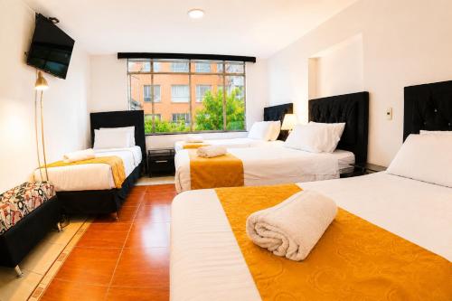 a hotel room with three beds and a window at House Studio Hotel in Bogotá