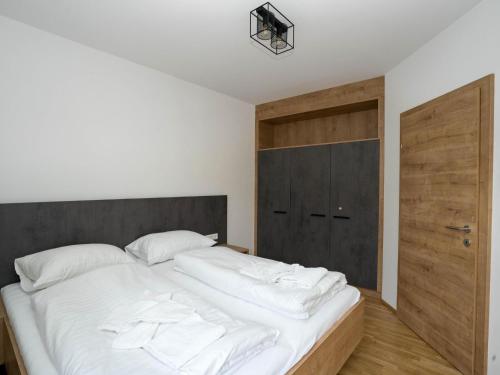 a bedroom with a large white bed with a wooden door at Murleben Top 06 in Stadl an der Mur