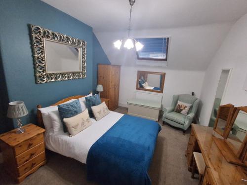 a bedroom with a king sized bed and a chair at Dunella Traditional Cottage in Callander
