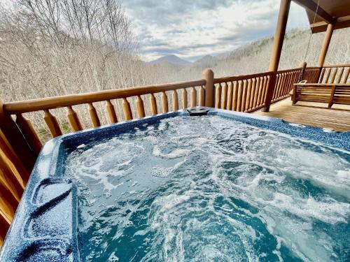 a hot tub on a deck with a bench at Absolute Bearadise cabin in Sevierville