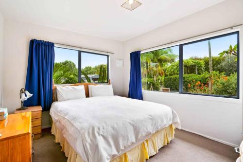 a bedroom with a bed and a large window at Pickmere Oasis in Kerikeri