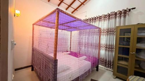 a bedroom with a pink canopy bed in a room at Blissful Chateau in Batigama