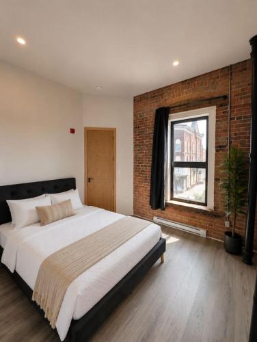 a bedroom with a large bed and a brick wall at The Post Hotel in Renfrew