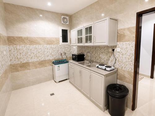 a small kitchen with white cabinets and a trash can at أرياف سويت in Al Baha