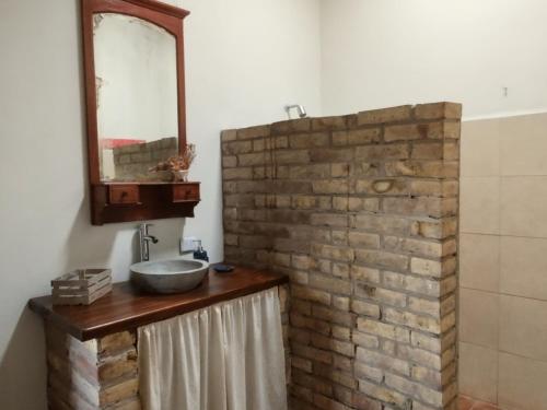 a bathroom with a sink and a brick wall at Refugio de Chacras in Ciudad Lujan de Cuyo
