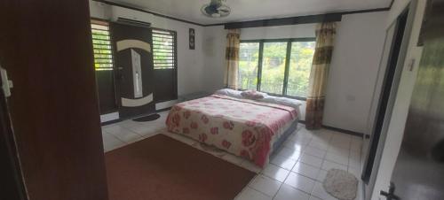 a bedroom with a bed in a room with windows at Ali's Homestay in Pacific Harbour