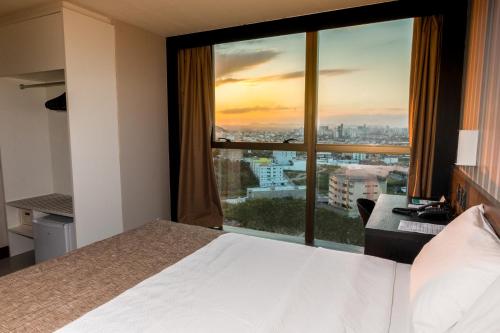ein Hotelzimmer mit einem Bett und einem großen Fenster in der Unterkunft WA Hotel Caruaru in Caruaru