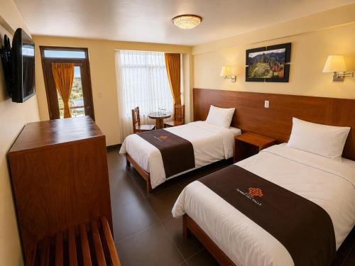 a hotel room with two beds and a television at Hotel Tambo del Valle in Urubamba