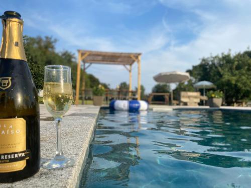 a bottle of wine and a glass next to a swimming pool at Quinta da Maínha - Charming Houses - com piscina privada in Braga