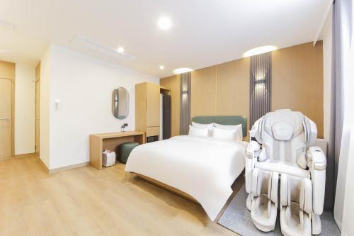 a bedroom with a white bed and a chair at 군산 비욘드 호텔 in Sinp'ung