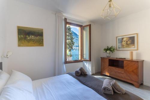 a white bedroom with a bed and a window at Romantic Pier by Rent All Como in Carate Urio