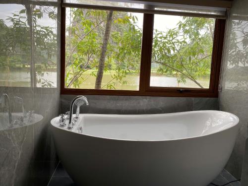 a bath tub in a bathroom with a window at Xuan Son Lakeside Bungalow in Ninh Binh