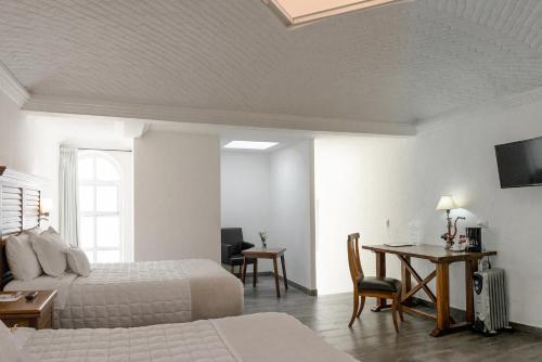 a bedroom with two beds and a desk and a table at Hotel La Morada in San Miguel de Allende