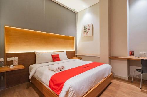 a bedroom with a large bed with a red blanket at RedDoorz Plus @ Doorman Guest House in Bandung