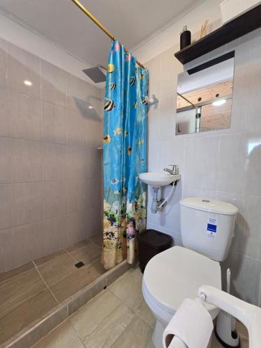 a bathroom with a toilet and a shower curtain at Hotel El Balcon de madera in Norcasia