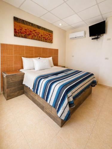 a bedroom with a bed with a tv on the wall at Hotel Tulipanes in Villahermosa