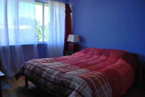 1 dormitorio con 1 cama con manta roja y ventana en La Casa Toesca, en Valdivia