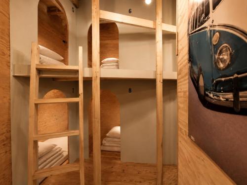 a room with bunk beds with an old car on the wall at Ishigaki Guesthouse HIVE in Ishigaki Island