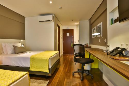 a bedroom with a bed and a desk with a phone at Quality Hotel Flamboyant in Goiânia