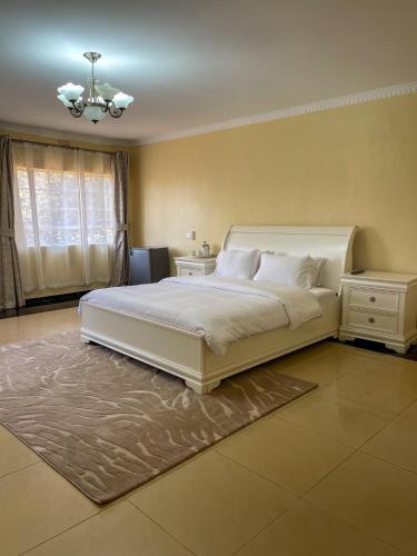 a bedroom with a large white bed and a chandelier at Royal Homes in Lilongwe