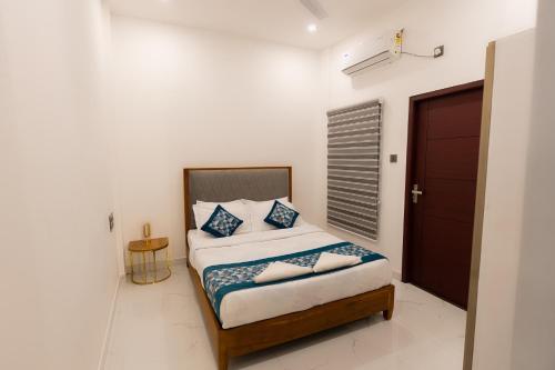 a bedroom with a bed with blue and white pillows at Rivera Residency , Kazhakuttom in Murukkumpuzha