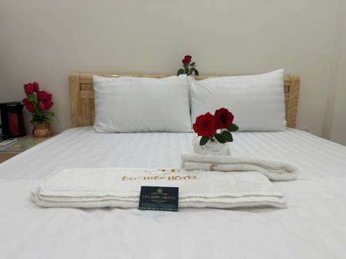 a bed with two towels and a vase with roses at Tân Hiệp 2 Hotel in Bùi Tiếng
