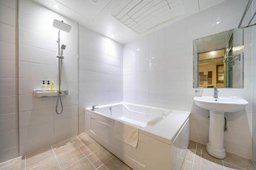a white bathroom with a sink and a bath tub at W Hotel in Yangsan