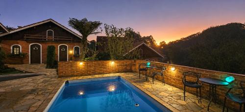 a pool with chairs and a table in front of a house at Pousada Palma Chalés in Monte Verde