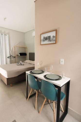 a bedroom with a bed and a table and chairs at 4-Studio Completo com Ar-Condicionado, TV e Lavanderia in Londrina