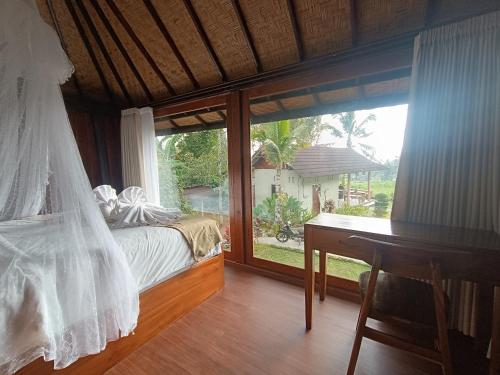 a bedroom with a bed and a desk and a window at Kacu Bali Munduk in Munduk