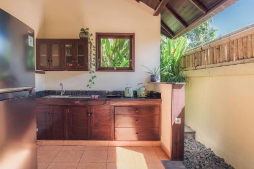 a kitchen with wooden cabinets and a sink at Villa KaRo Pemuteran in Pemuteran