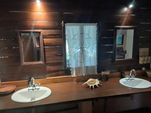 a bathroom with two sinks and a butterfly shower curtain at Boraha Village Ecolodge in Ambodifototra