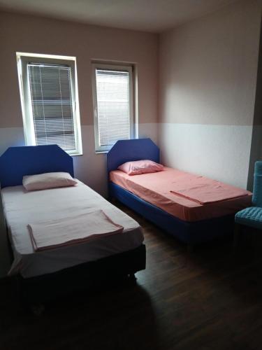 two beds in a room with two windows at Sokak in Struga