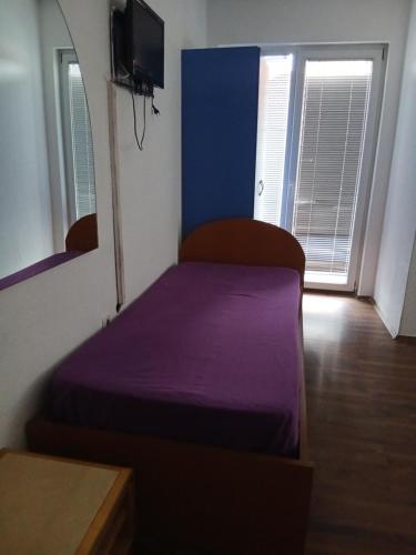 a small bedroom with a purple bed and a tv at Sokak in Struga