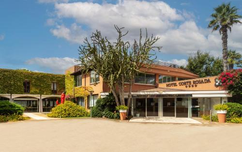 ein Hotel mit einem Baum vor einem Gebäude in der Unterkunft Hotel Corte Rosada - Adults Only, Affiliated by Meliá in Porto Conte