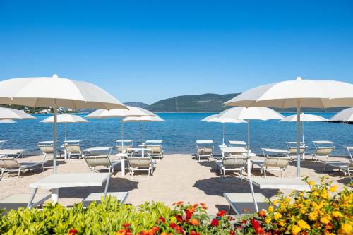 eine Gruppe von Stühlen und Sonnenschirmen an einem Strand in der Unterkunft Hotel Corte Rosada - Adults Only, Affiliated by Meliá in Porto Conte