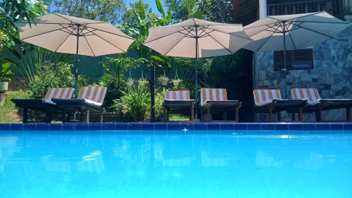 a group of chairs and umbrellas next to a swimming pool at Machan Villa in Tangalle