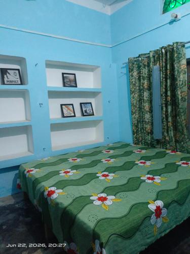 a bedroom with a green bed with flowers on it at Shri chitrakoot homestay in Chitrakoot