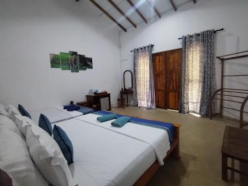 two beds in a room with two windows at Wilpattu Wild Villa in Pahala Maragahawewa