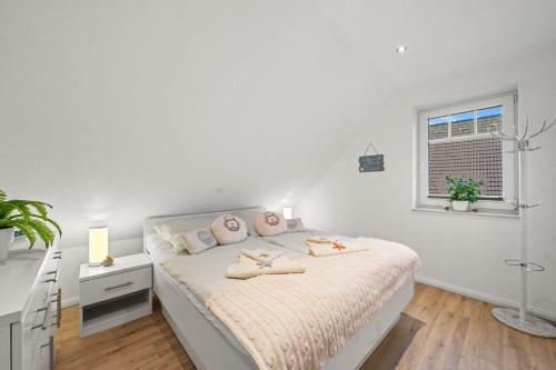 a white bedroom with a bed and a window at Am-Nordmeerstrand in Norddeich