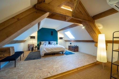 an attic bedroom with a bed and a blue wall at Le Chai des Écluses 4-étoiles gîtes in Saint-Léger-sur-Dheune