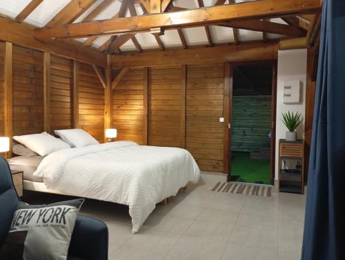 a bedroom with a large white bed and wooden walls at Lodge de Charme Vue Imprenable in Le Robert