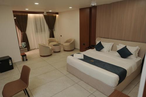 a bedroom with a large bed and chairs in it at Empire Suites in Erāttupetta