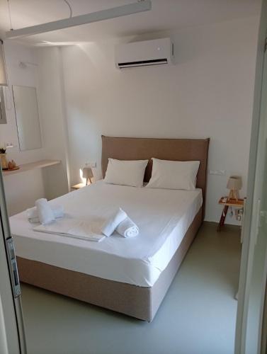a bedroom with a large bed with white sheets and pillows at Almira Seaside Suites in Áyios Dhimítrios