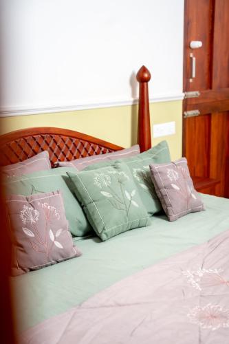 a bed with pink and green pillows on it at Illam By Santhi in Varkala