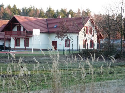 a white house with a red roof in a field at Penzion Lipina in Slatiňany