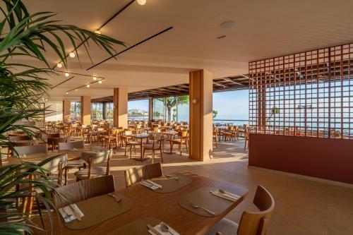 a restaurant with tables and chairs and a view of the ocean at Hotel Blue Sea Beach, Affiliated by Meliá in Stalís